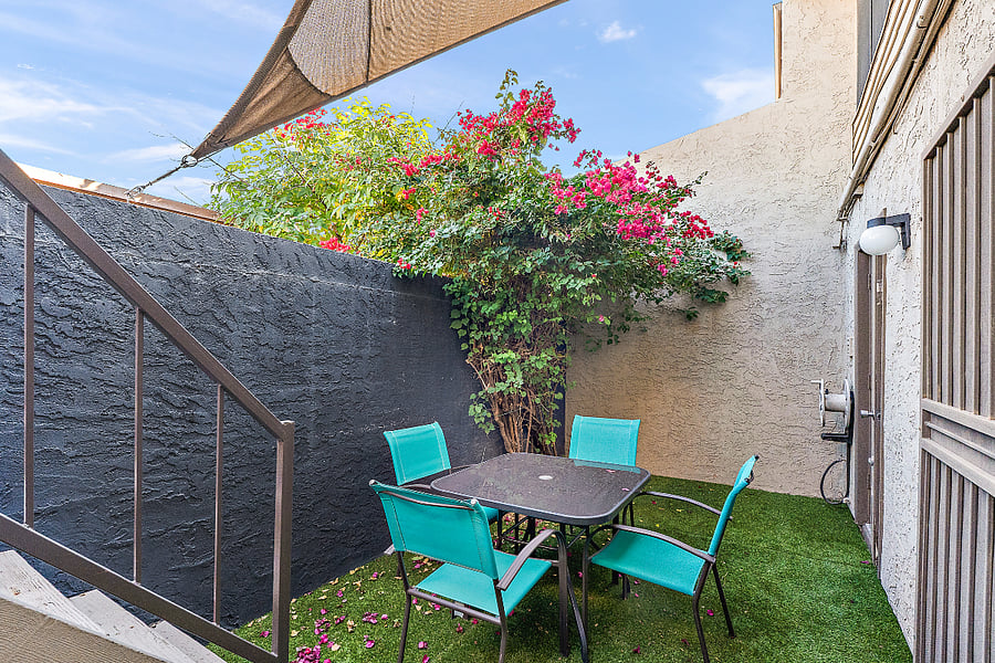 Lets talk about your outdoor space. Tucked away and completely enclosed, this patio is your private headquarters. Its shielded by a custom shade sail and features a massive, vibrant bougainvillea that gives you that perfect pop of Scottsdale color.
We skipped the dirt and went straight to clean, zero-maintenance turf. With a dedicated outdoor dining setup, its the exact spot you want to be drinking your morning coffee in total peace or splitting a bottle of wine after the sun goes down. Plus, it serves as the ultimate connecting hubthe stairs lead right up to the loft office's private entrance, and the ground-level doors open straight to the laundry room and main floor bedroom. Its private, highly functional, and completely hidden from the neighbors.