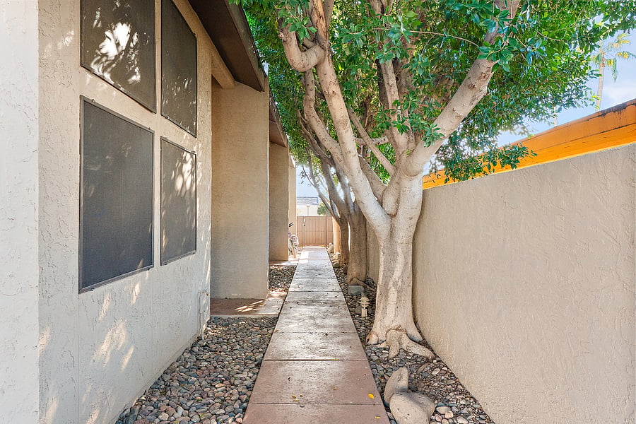 Lets talk about the walk from your covered parking spot to the front door. If youve ever survived a Scottsdale summer, you know a 30-second walk in direct sunlight can ruin your day. Not here. You get a private, paved walkway flanked by river rock and completely shielded by a massive canopy of mature trees. Its basically a shaded tunnel that keeps the Arizona sun off your neck before you even turn the key.Lets talk about your outdoor space. Tucked away and completely enclosed, this patio is your private headquarters. Its shielded by a custom shade sail and features a massive, vibrant bougainvillea that gives you that perfect pop of Scottsdale color.
We skipped the dirt and went straight to clean, zero-maintenance turf. With a dedicated outdoor dining setup, its the exact spot you want to be drinking your morning coffee in total peace or splitting a bottle of wine after the sun goes down. Plus, it serves as the ultimate connecting hubthe stairs lead right up to the loft office's private entrance, and the ground-level doors open straight to the laundry room and main floor bedroom. Its private, highly functional, and completely hidden from the neighbors.
