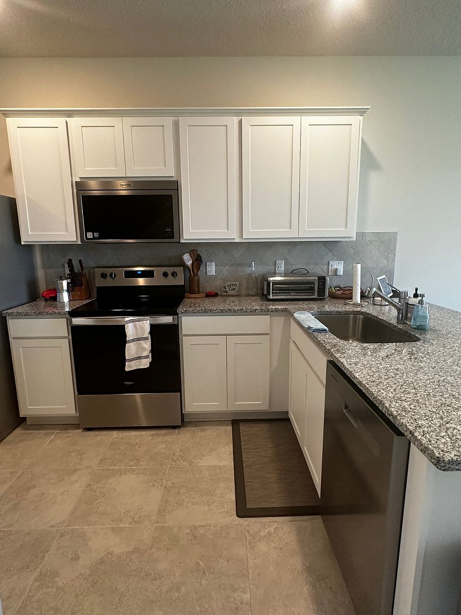 Kitchen includes stainless steel appliances: fridge, stove, microwave, and dishwasher.