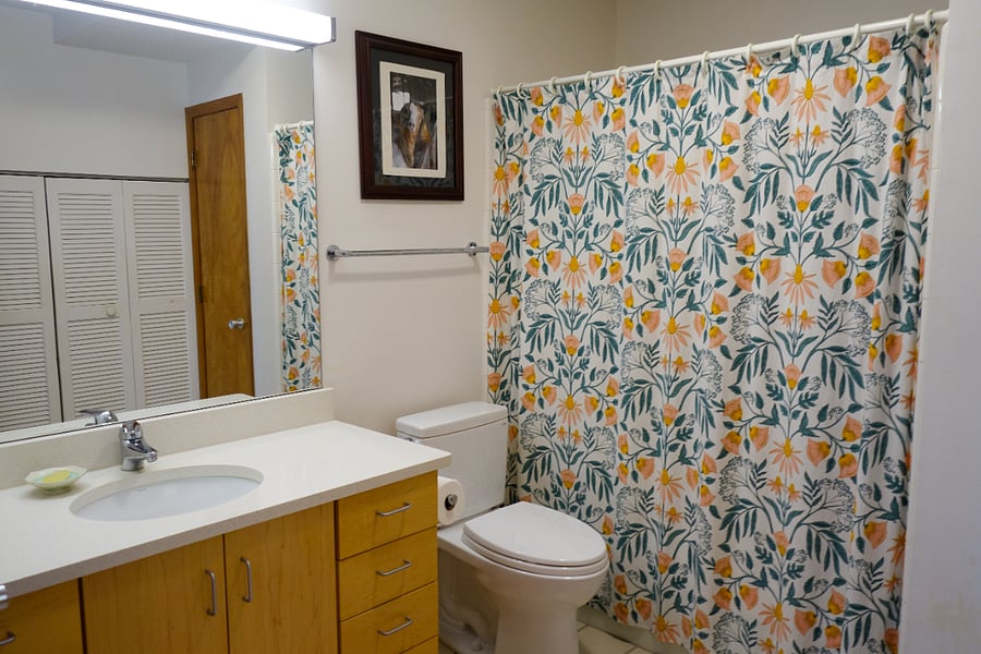Broader view of the bathroom, which contains a large vanity which contains many drawers, most are empty for you.  A few contain a hair dryer, curling iron, and heating pad.  There are also cleaning supplies.