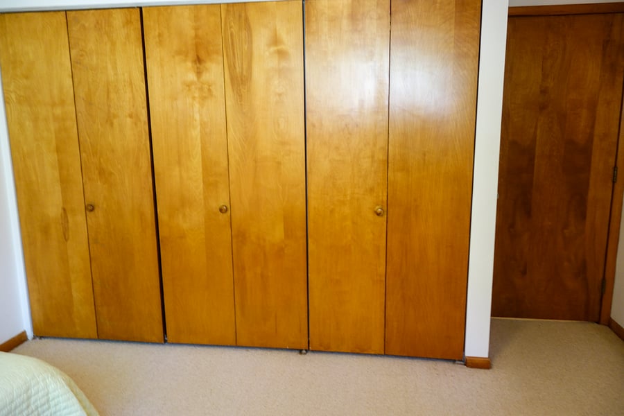 One wall of the room is beautiful wooden closets and the door into the room.