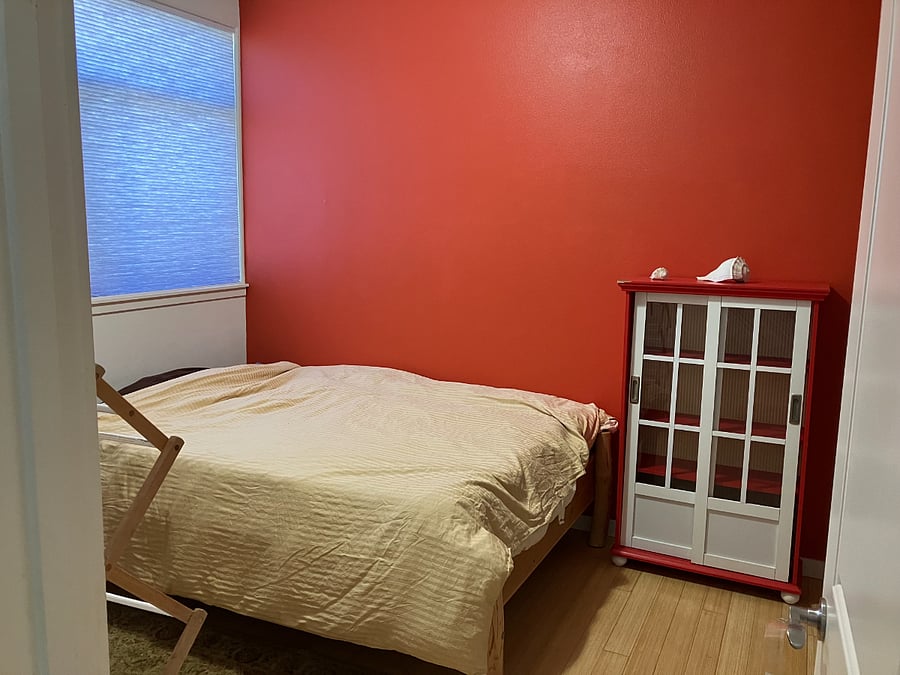 Second bedroom has a bookshelf, wall cubbies, extra storage above the closet, bed linens, and blackout curtains.