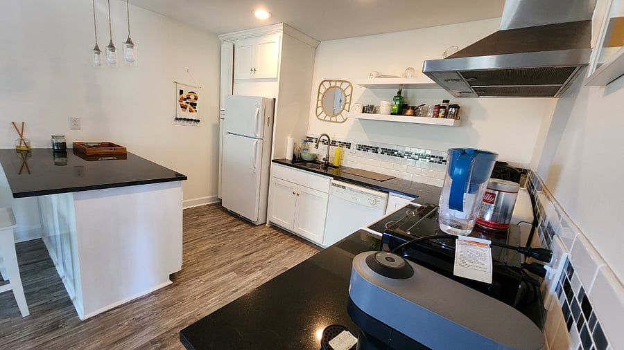 View of equipped kitchen with full refrigerator, dishwasher and granite