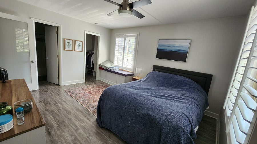 Bedroom with queen sized bed, walk-in closet near window with bench