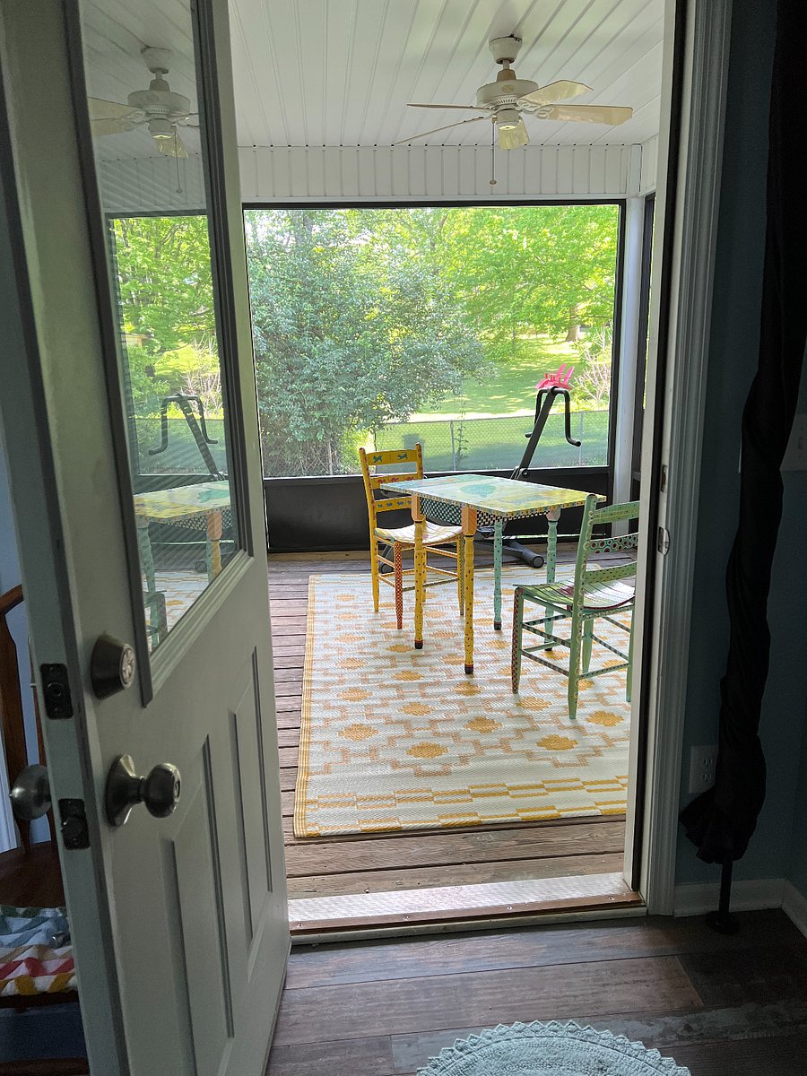 Table, two chairs and an exercise bike on the screened in porch.