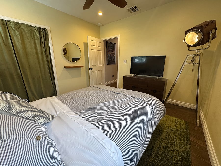 40'' Smart TV in guest bedroom with cool mid century spotlight tripod lamp.