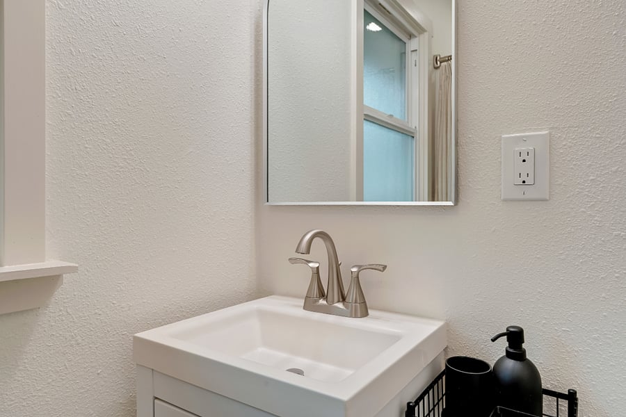 Bathroom contains multiple storage options (under sink, wall shelves, hooks, and corner shelf)