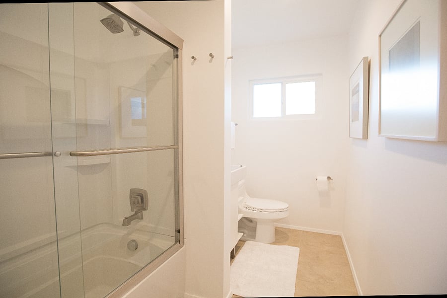 Guest bathroom features shower/tub combo and stacked washer and dryer.
