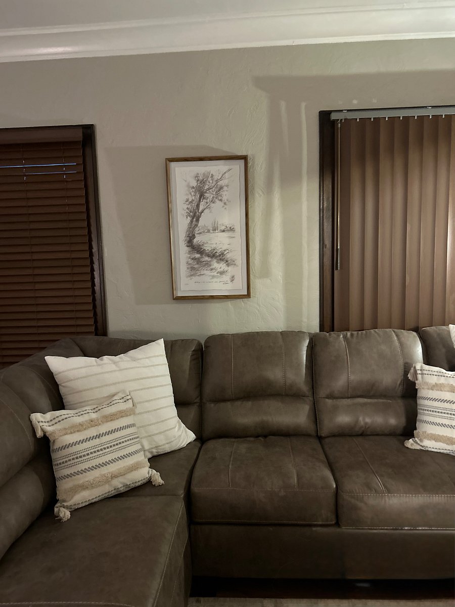 Wall art behind couch between large windows facing front yard. 
