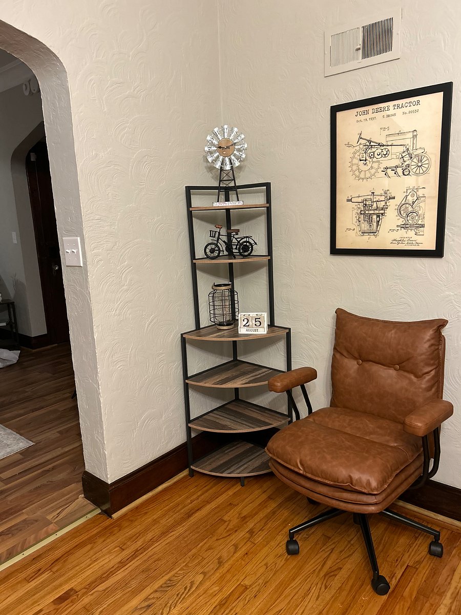 Corner book shelf and wall art play into the John Deere decor and industrial theme that's carried throughout the unit. This corner is on the same wall as the French doors that lead into your large bedroom. 

The chair will sit behind the office desk and have two large accent chairs that face it. 