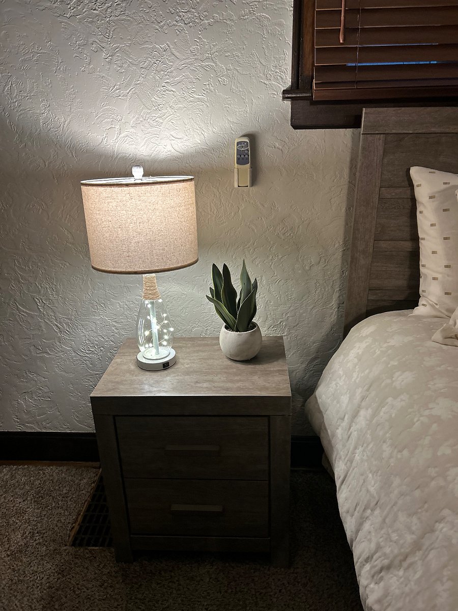 Nightstand in bedroom with simple greenery. 