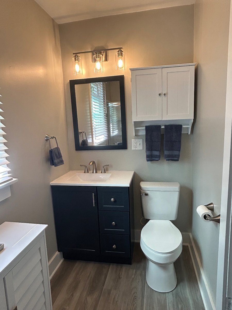 Picture of the bathroom vanity and wall storage with the light on. 