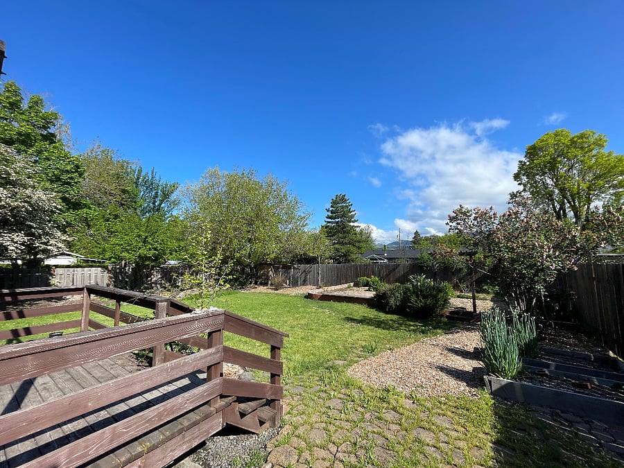 backyard including deck at propane BBQ, fruit trees and an opportunity to grow your own food.