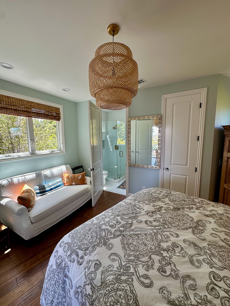 Bedroom with view of couch under windows facing South, door into bathroom.