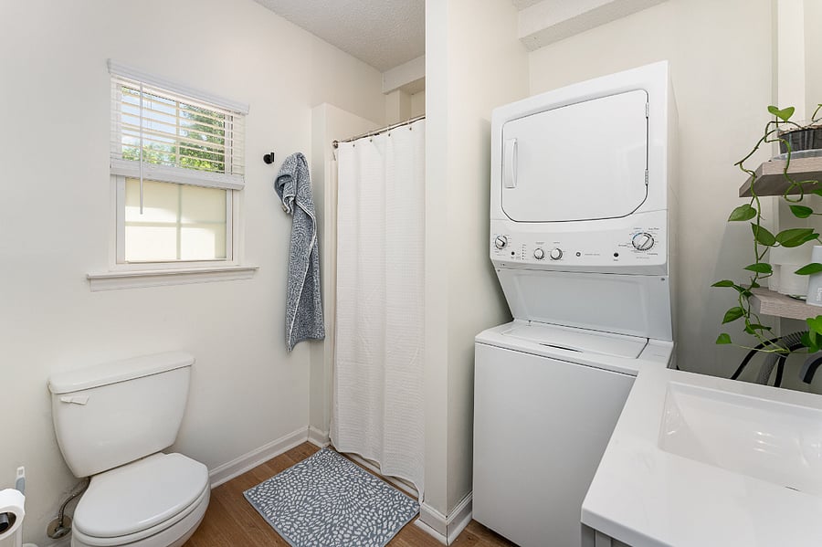 Full bathroom with in-unit washer/dryer, shower, large mirror, and shelving