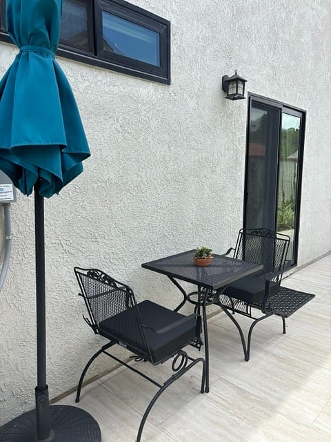 Private patio with bistro table, two chairs with cushions, patio umbrella. The sliding door in the background is the private entrance to the room.