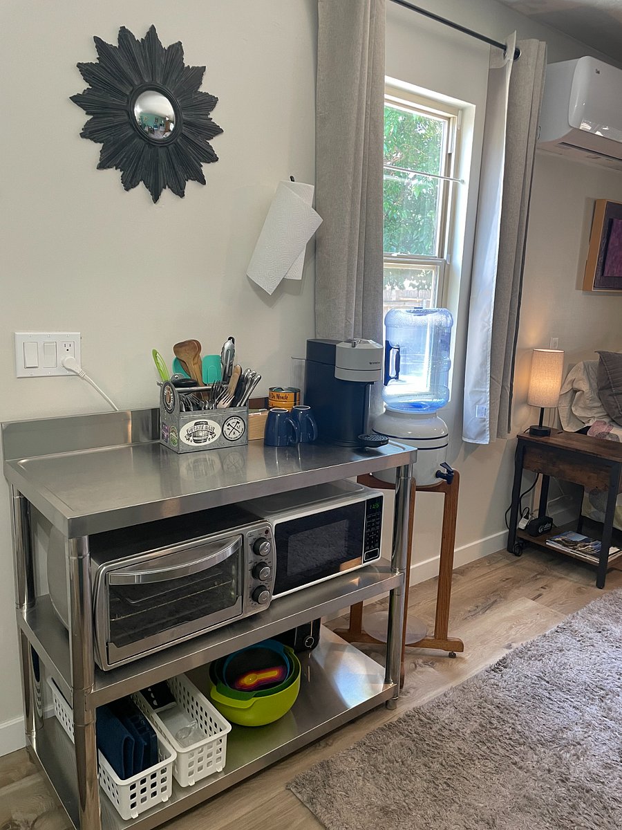 Kitchen work table with Nespresso maker, toaster oven, microwave, other dishes and utensils.