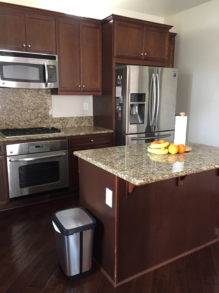 Kitchen cabinets and drawers next to the refrigerator are yours with dishes, cups, glasses, silverware