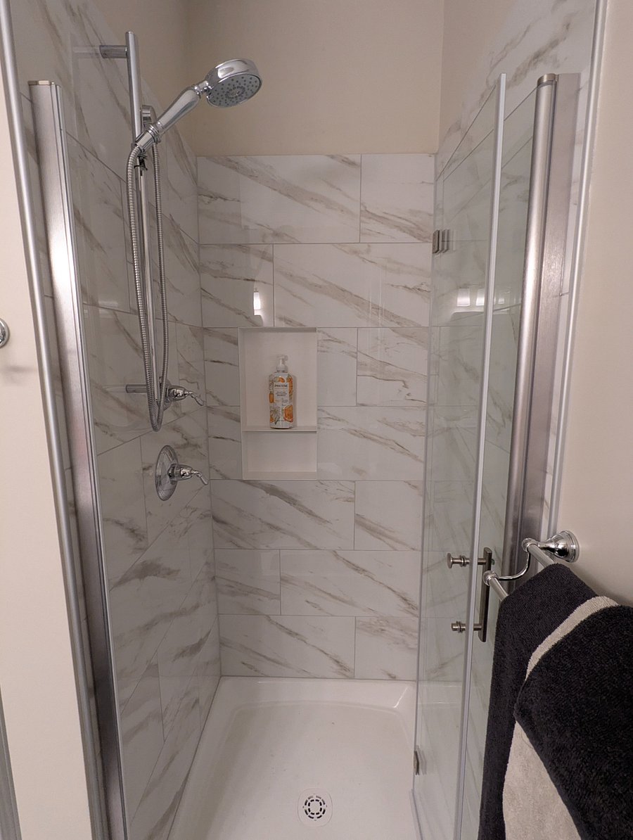 Tiled shower with hand shower on height-adjustable rail