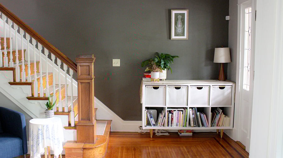 The grand foyer is warm and inviting with books, plants, and soft textures. 