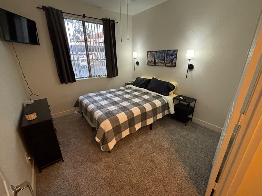 Bedroom 3 with queen bed, mounted smart tv, blackout curtains, noise machine, ceiling fan and remote control lights.
