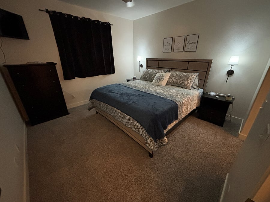 Bedroom 2 with king bed, mounted smart tv, blackout curtains, noise machine, ceiling fan and remote control lights.