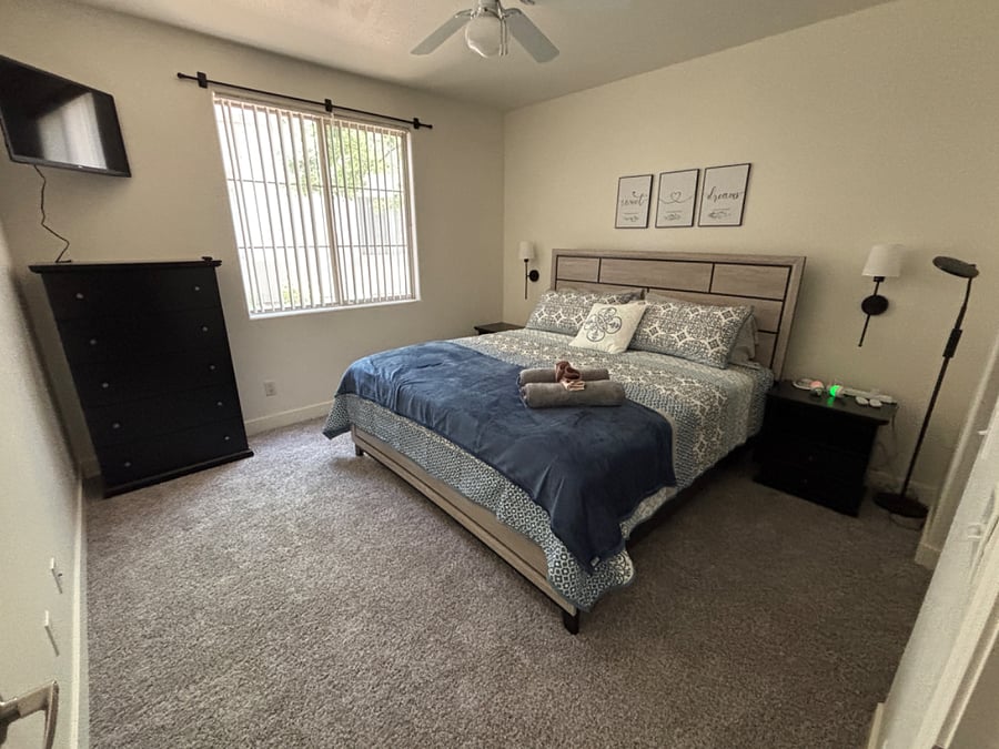 Bedroom 2 with king bed, mounted smart tv, blackout curtains, noise machine, ceiling fan and remote control lights.