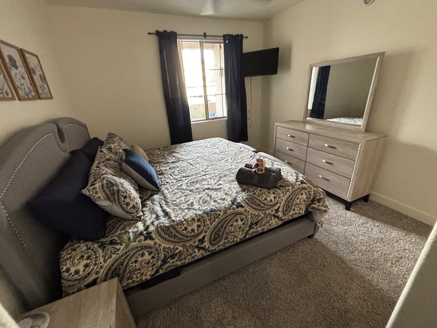 Primary bedroom with view of the patio and plenty of natural light...king bed, mounted smart tv, blackout curtains, noise machine, ceiling fan and remote control lights.