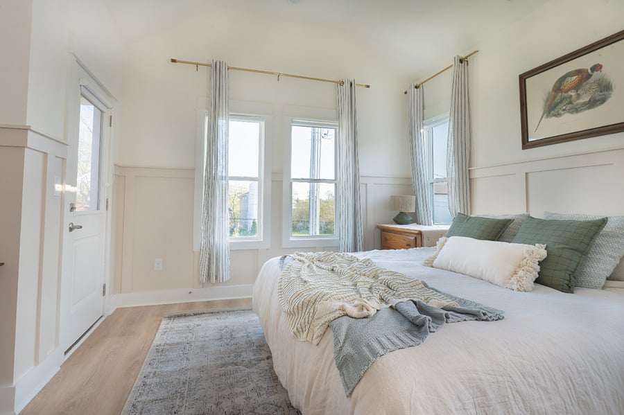 Primary bedroom featuring king bed, small balcony, smart TV, and writing desk. Flooded with natural light throughout the day