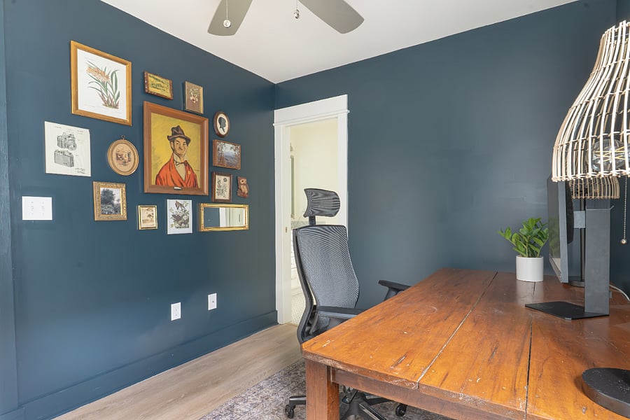 Upstairs office equipped with large desk, office chair, monitor, and background for video conferencing