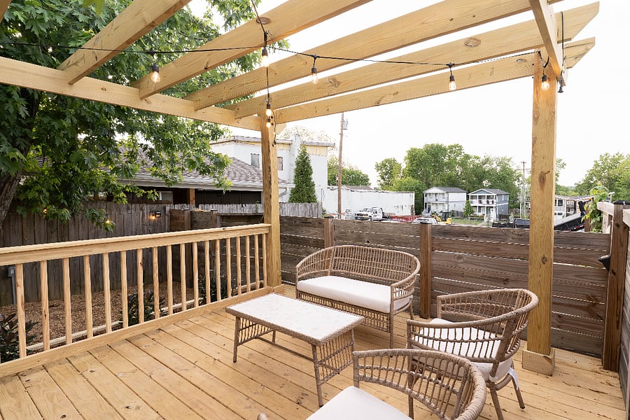 Fenced backyard with seating area, pond, and fire pit. Somewhat private from the neighbors thanks to the trees but still visible on either side