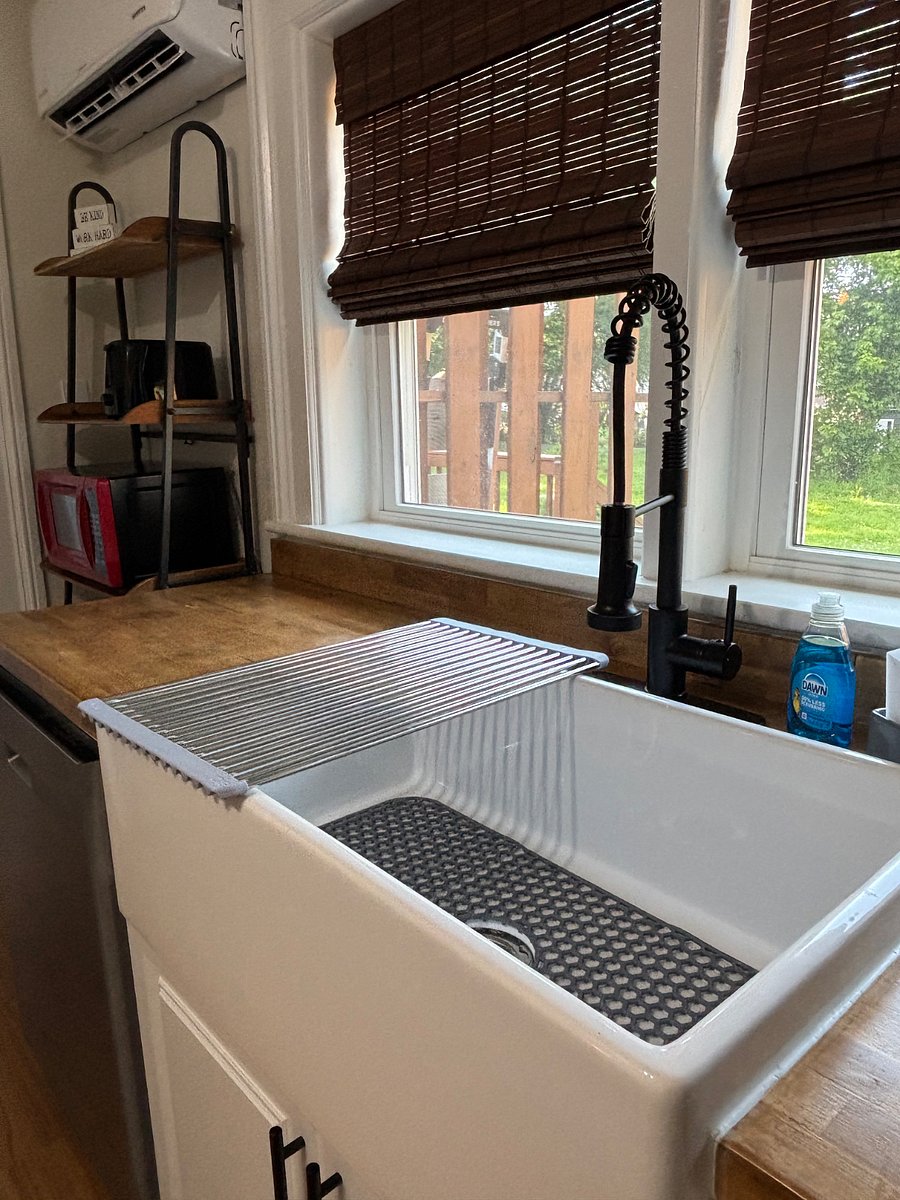 Large farm sink with commercial spray faucet and dishwasher.