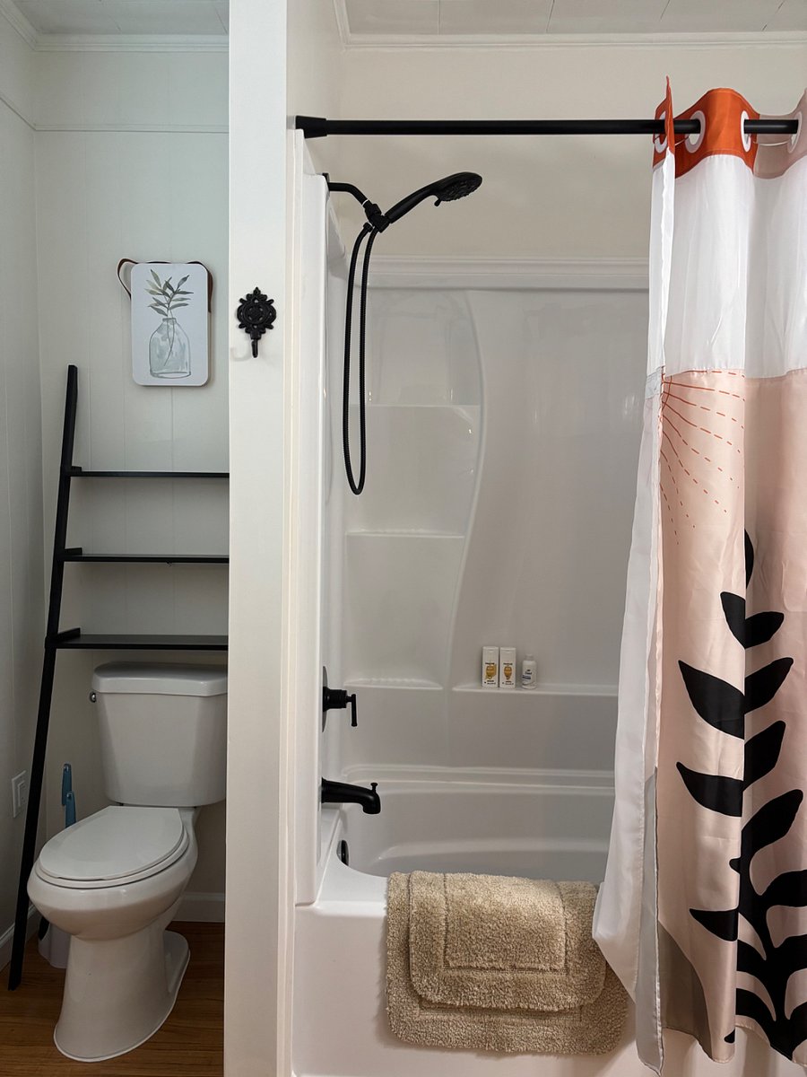 Bathroom with bath shower combo and has lots of shelves for storage.