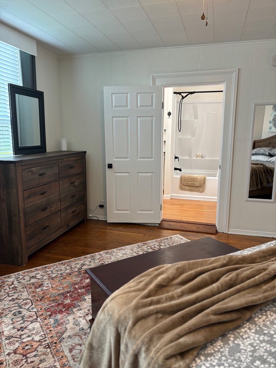 Black out curtains and has large dresser with mirror and another matching chest of drawers to the left. (not shown)