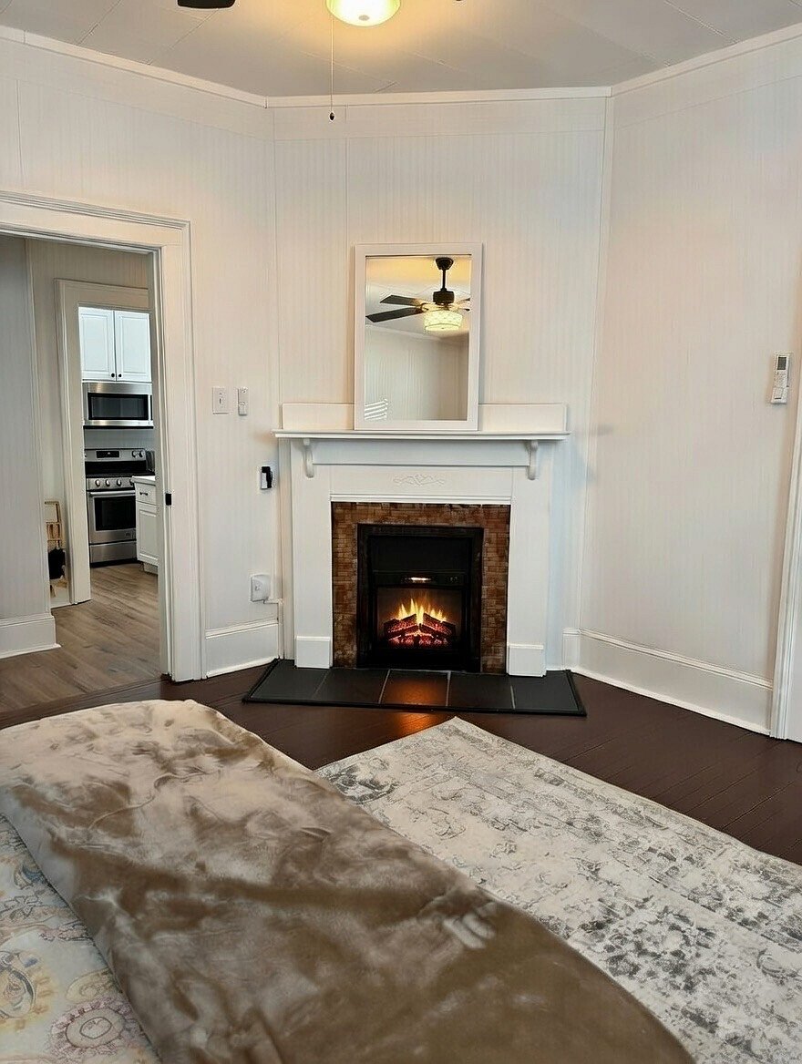 Bedroom with a queen bed and electric fireplace for ambience. Giant walk in closet for storage and has a dresser and chest of drawers.