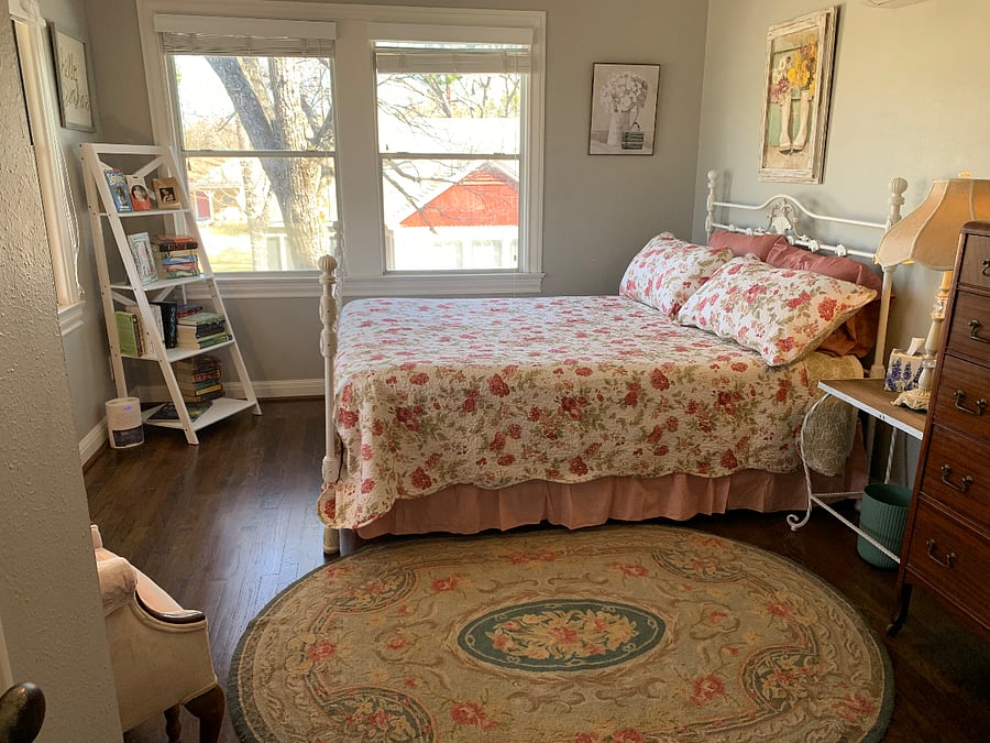The Pink Bedroom features a queen bed with a new mattress, a beautiful view of the sunset, antique dressers, a comfortable sitting chair, and cozy charm.