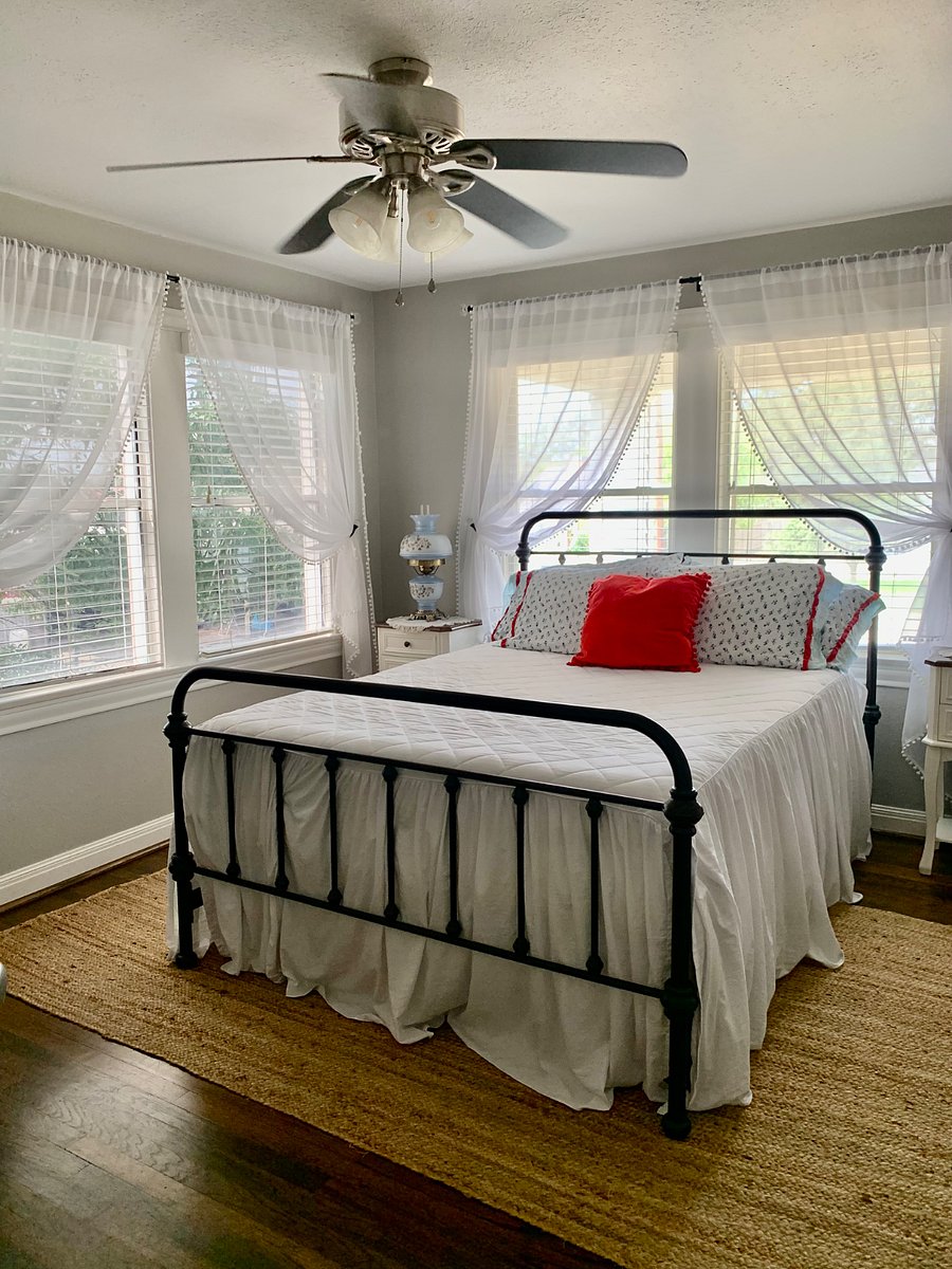 The Farmhouse bedroom features a queen bed with a new mattress, an antique dresser and lamps, and a view of the sunset from the second floor.
