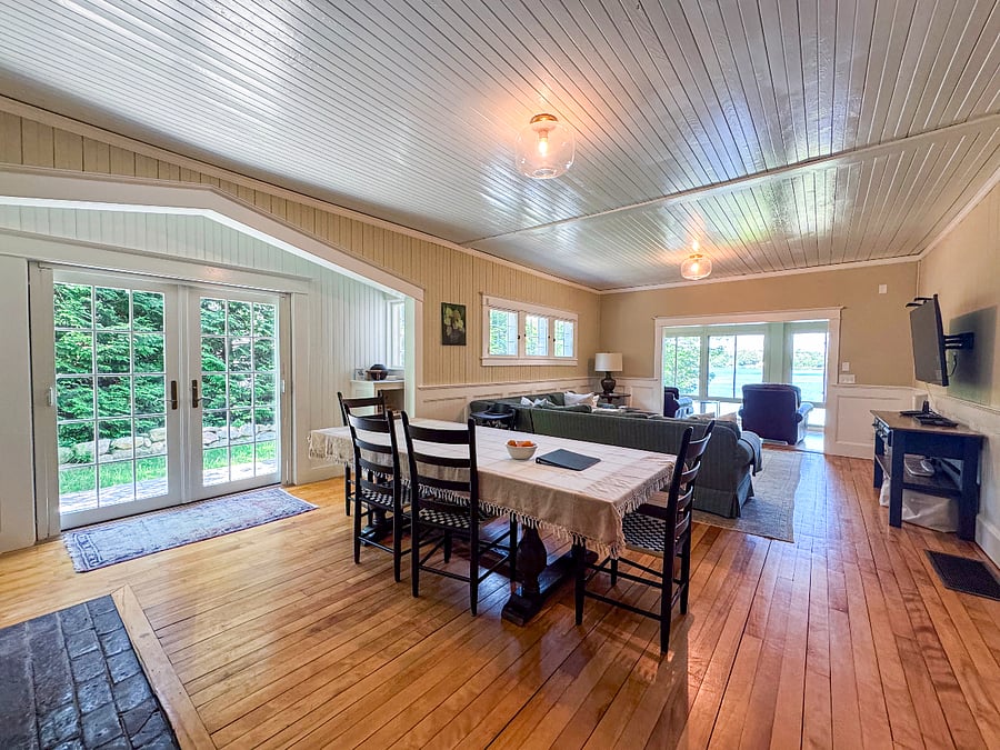 Living and dining area with original 1905 fireplace, smart tv and lake view from sunroom
