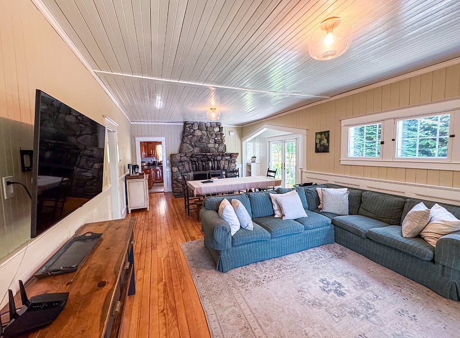 Living and dining area with original 1905 fireplace, smart tv and lake view from sunroom