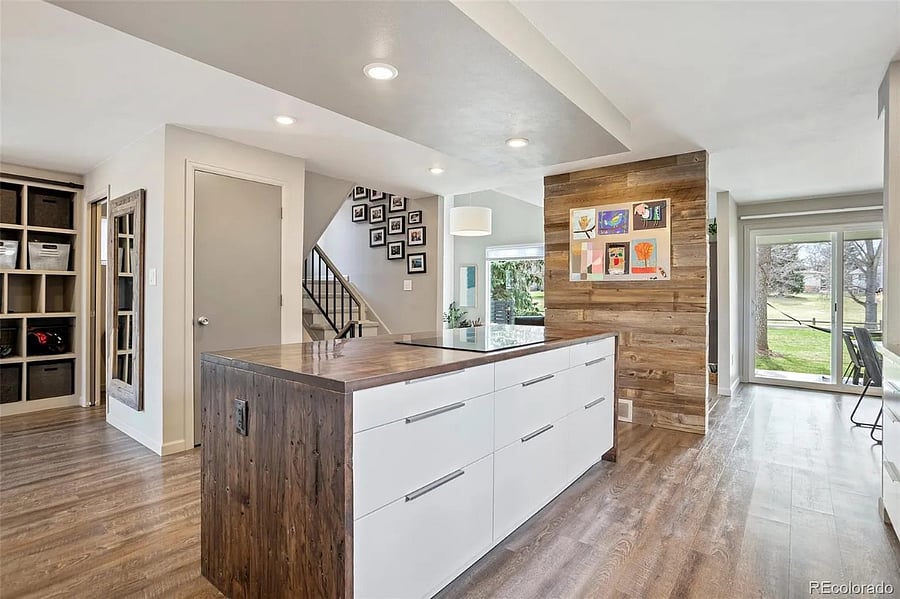 sliding half-bath door visible on the left. Kitchen island and view into the living and dining room facing the park.