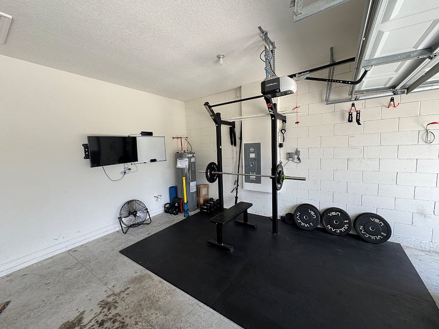 Garage gym with weights, TV, and fan. 