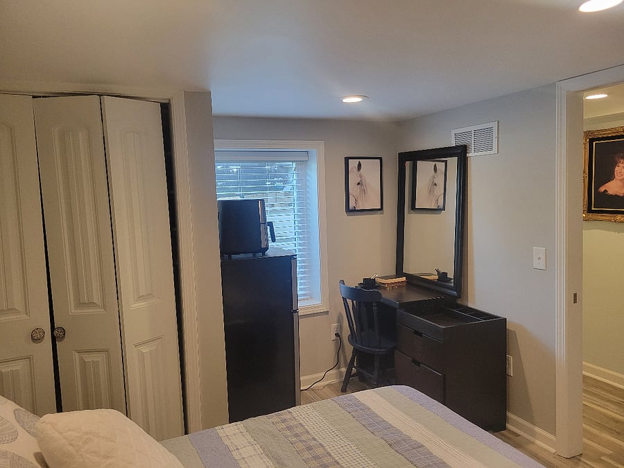 basement bedroom with big window, full size bed with storage underneath, closets designed by California closets.