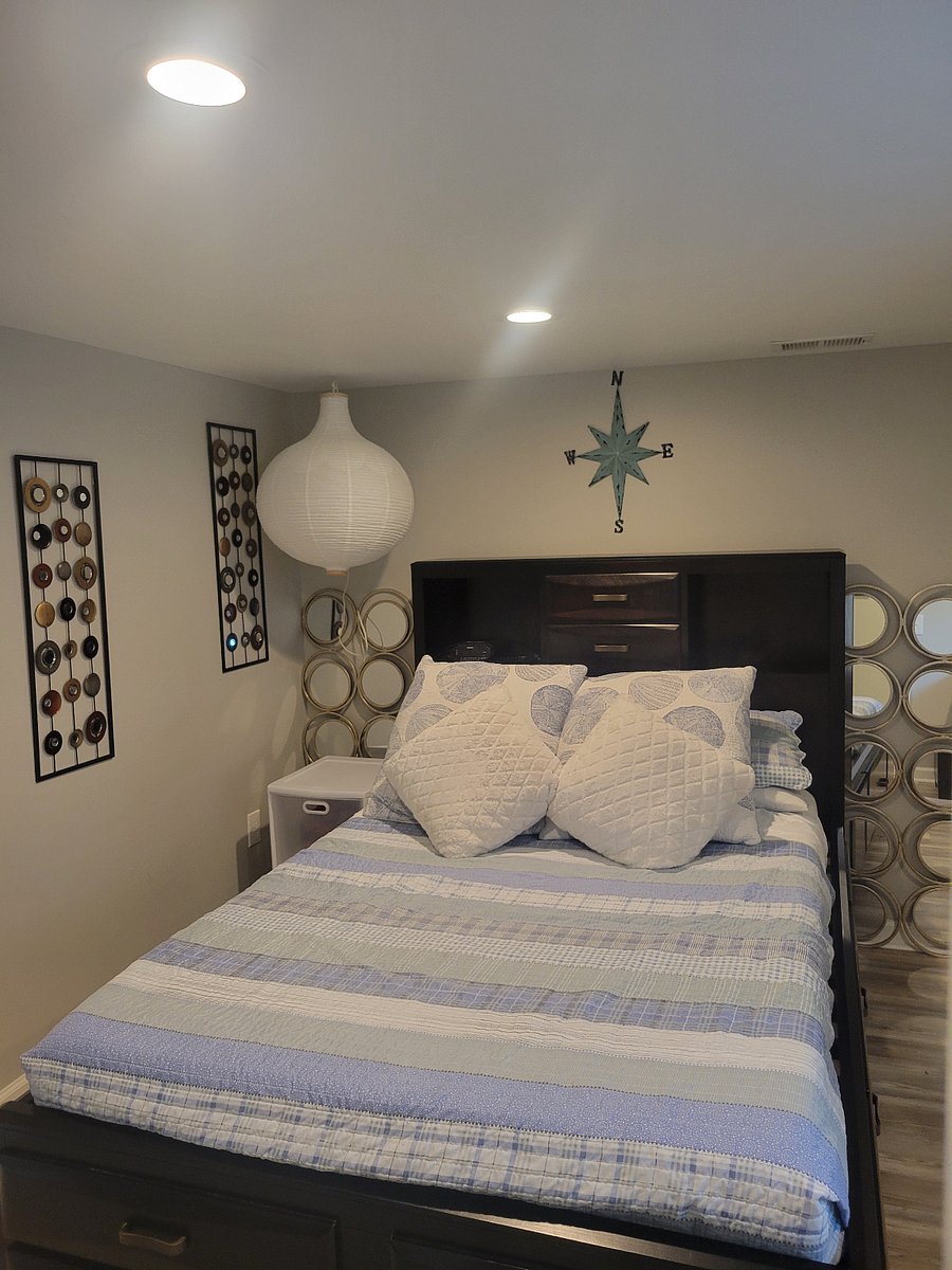 full size bed with storage, small refrigerator and desk with mirror and another full length mirror on other (basement bedroom)
