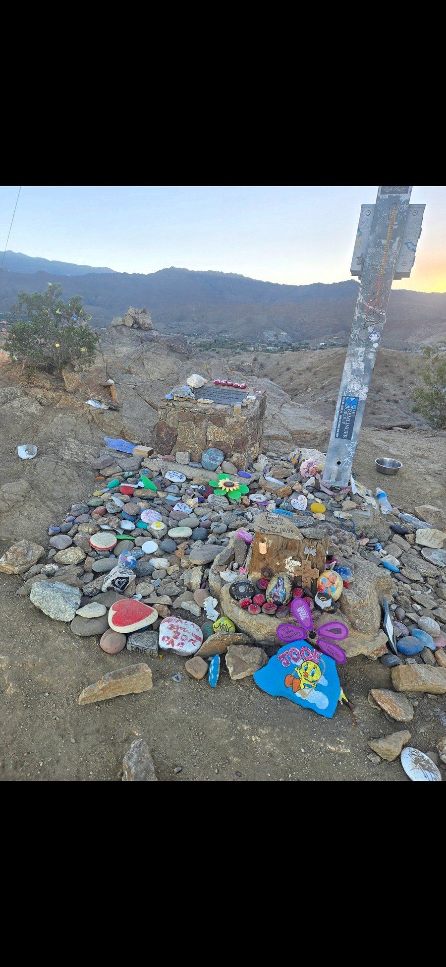 People being ricks and trinkets to memorialize thier lived ones at the foot of the Cross at the end of the hiking trail.