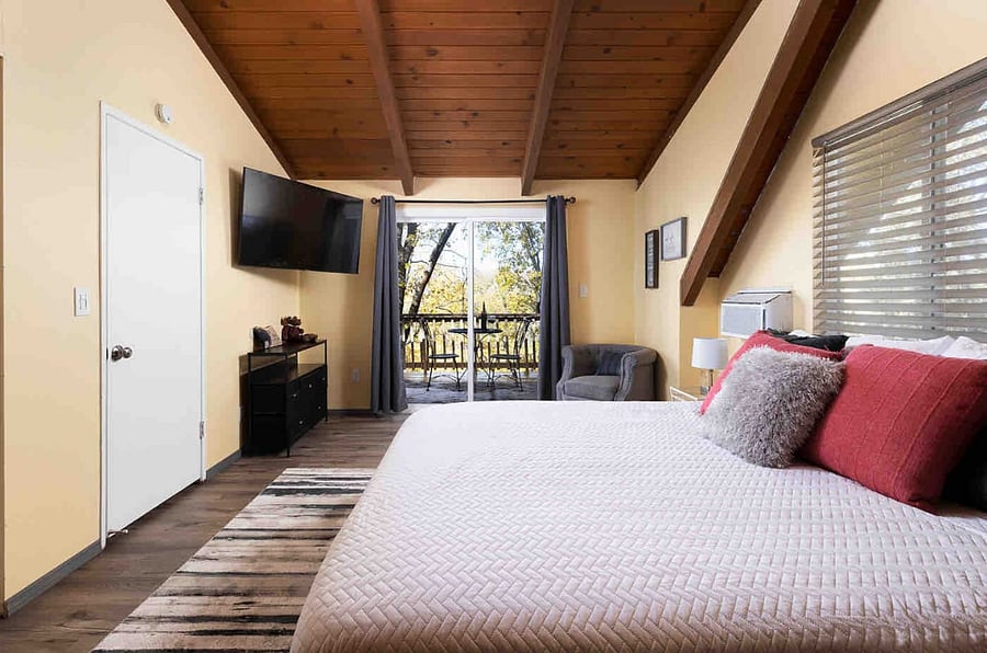 The spacious primary bedroom has its own private balcony in the treetops to enjoy a glass of wine or morning coffee with the view