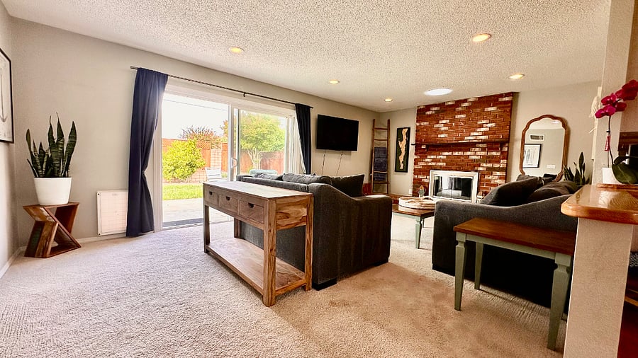Beach-themed living room with cozy couches, and sliding door to the backyard