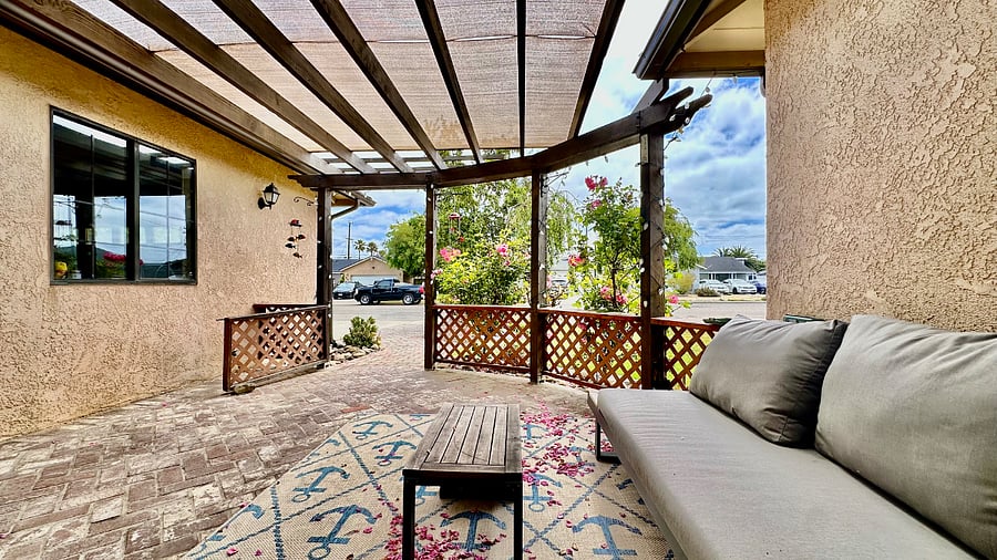 Front patio lounge furniture surrounded by bright roses, front lawn, and birch tree for a peaceful place to enjoy coffee or an after work beverage.