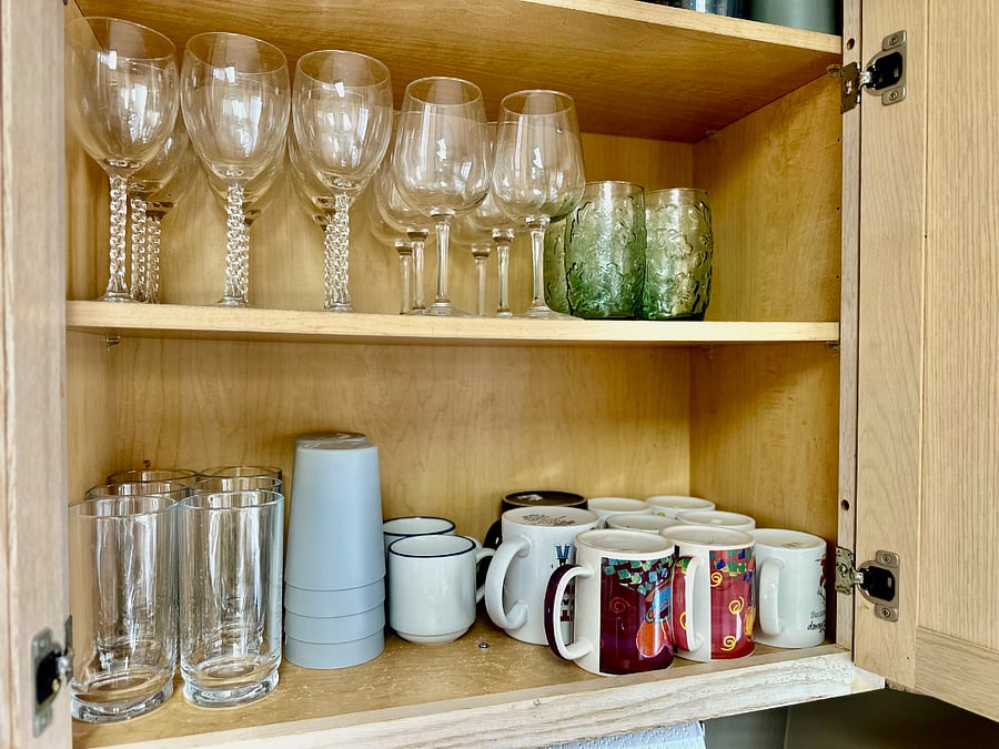 Kitchen stocked with glasses, mugs, wine glasses, plastic cups, serveware, cookware, baking utensils, and more.
