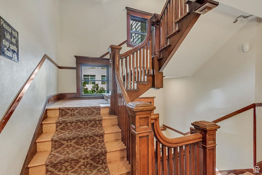 Hand-carved newel posts along the wooden stairs beside a large picture window.