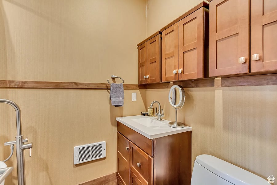 Vanity, wall-mounted cabinets, and low-profile toilet in warm wood tones.